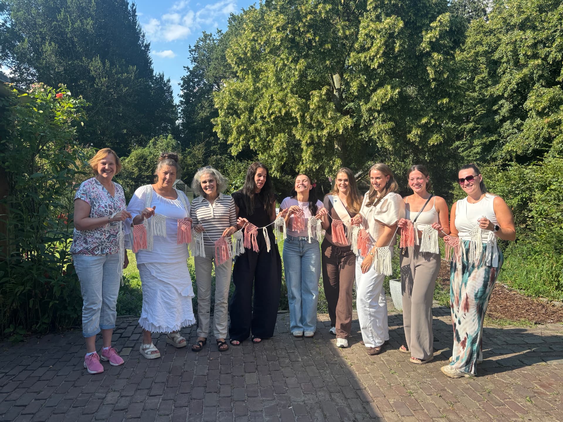 Groep vrouwen in de tuin met hun zelfgemaakte macramé slingers