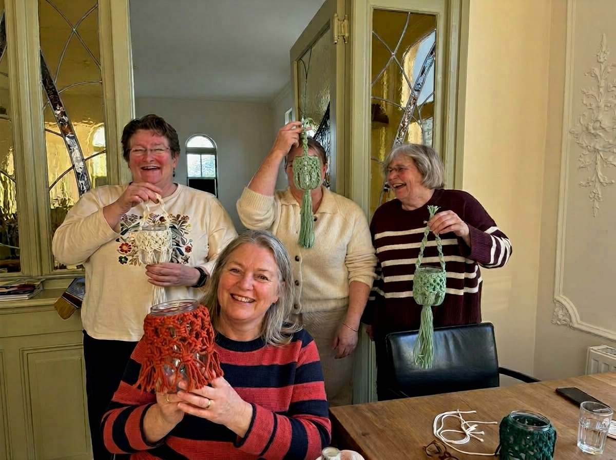 Vriendinnen tonen lachend hun macramé creaties tijdens een workshop